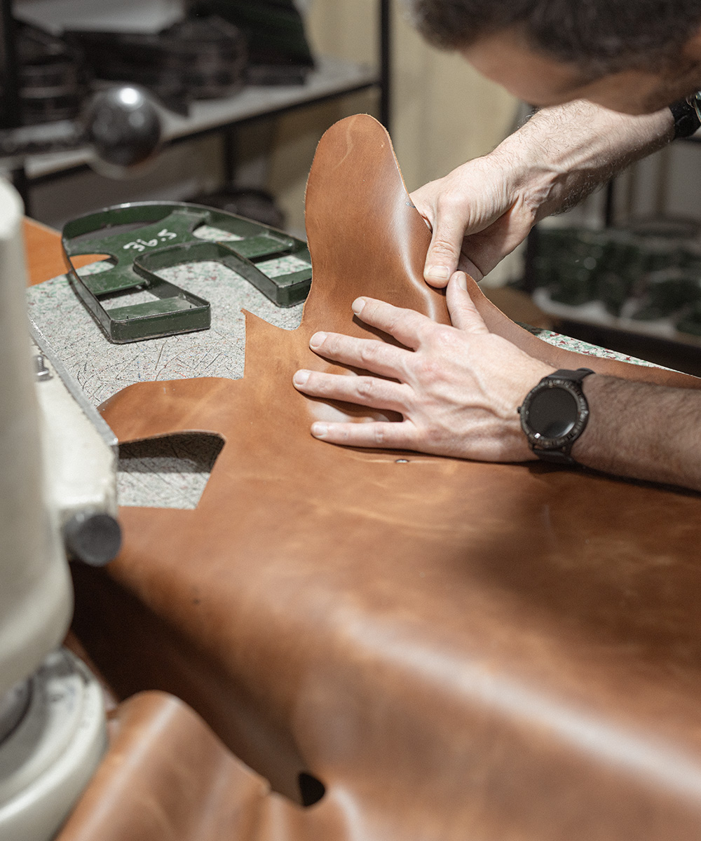 Craftsman easing full-grain leather around a cutting die in the Ede atelier